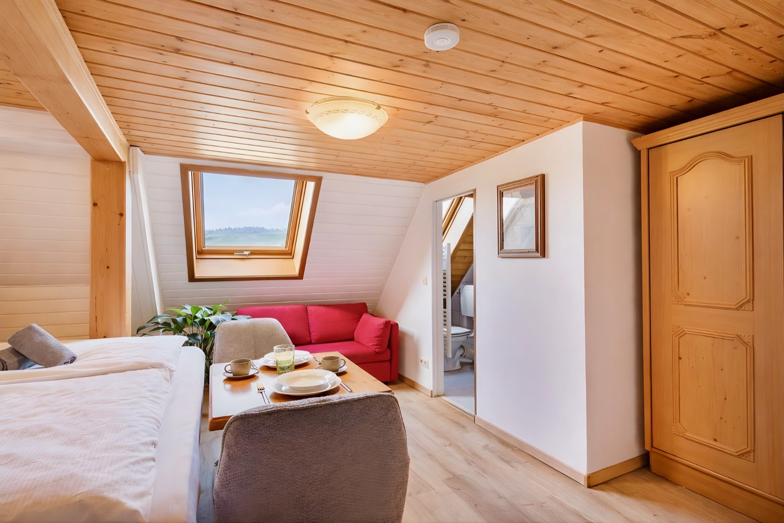 Wohnbereich mit rotem Sofa und Dachfenster