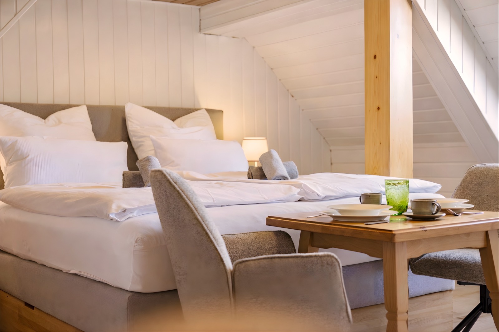Bett mit weißer Bettwäsche und gedecktem Tisch